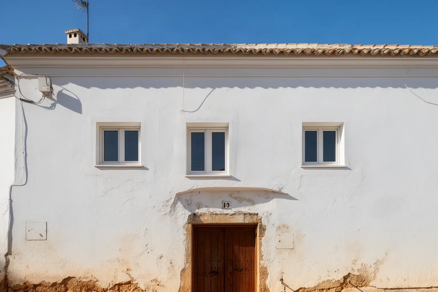 Fachada encalada de una vivienda en Benacazón con ventanas nuevas